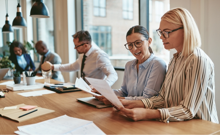 two financial professional women sitting and review paperwork together
