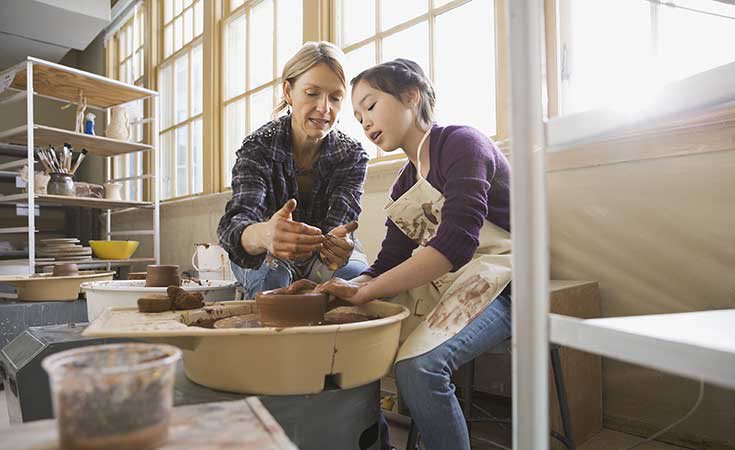 woman teaching child to make pottery